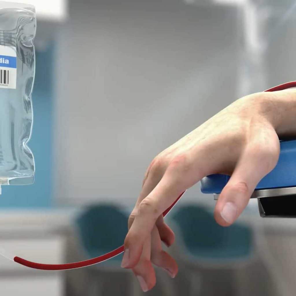 3D animated close-up of a patient’s hand during a medical infusion procedure, with IV bag and tubing.