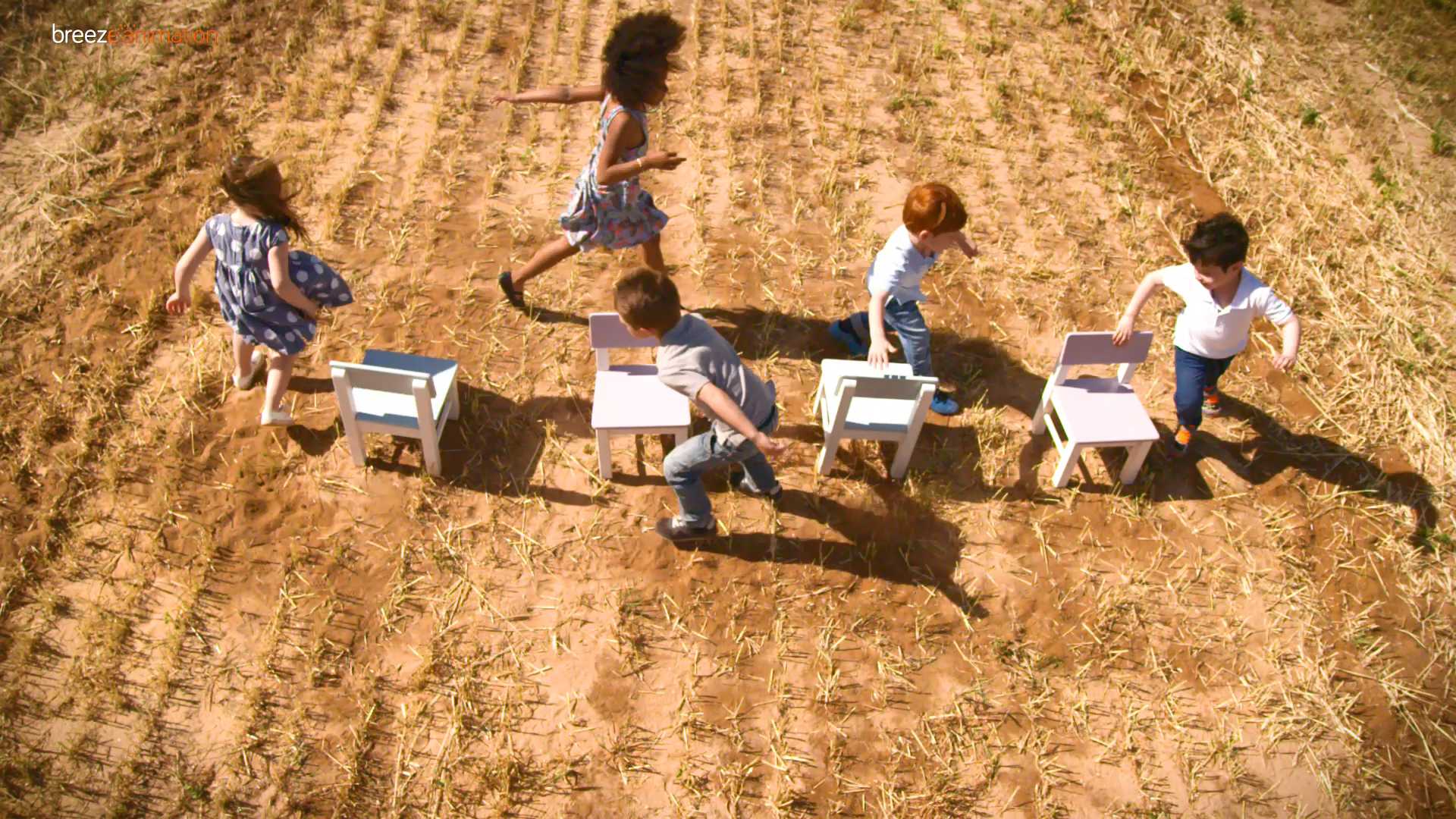 Children playing musical chairs in a dry field, symbolizing competition over limited resources.