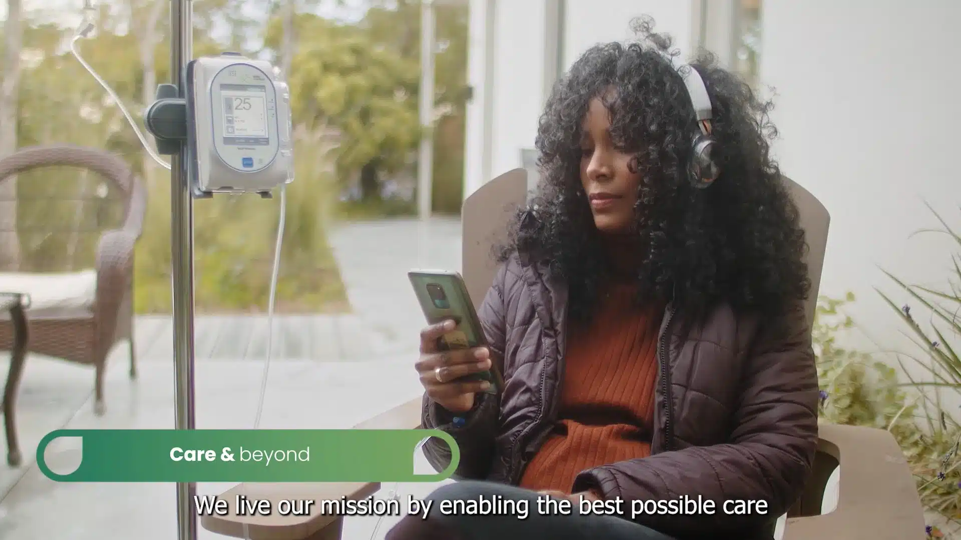 Woman receiving infusion therapy at home while using a smartphone and wearing headphones